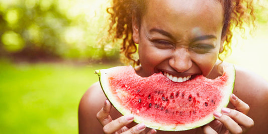 A person outdoors holds a slice of watermelon