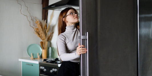 A person opening a modern fridge in a well-lit, contemporary kitchen