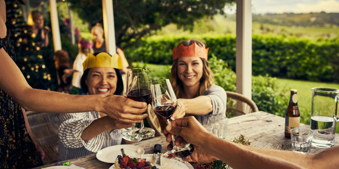 people sharing a meal outdoors, raising their wine glasses in celebration