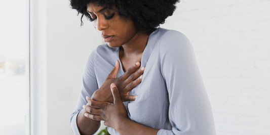 woman suffering from heartburn and holding on tightly to her chest in pain