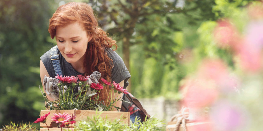 woman gardener outside in her garden smelling flowers