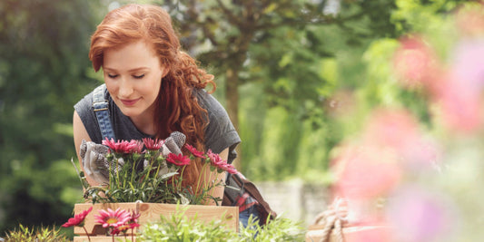 woman gardener outside in her garden smelling flowers