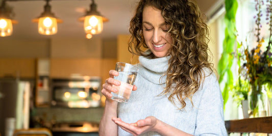 A person holding a glass of water in a well-lit kitchen