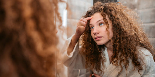 a person with curly hair standing in front of a mirror